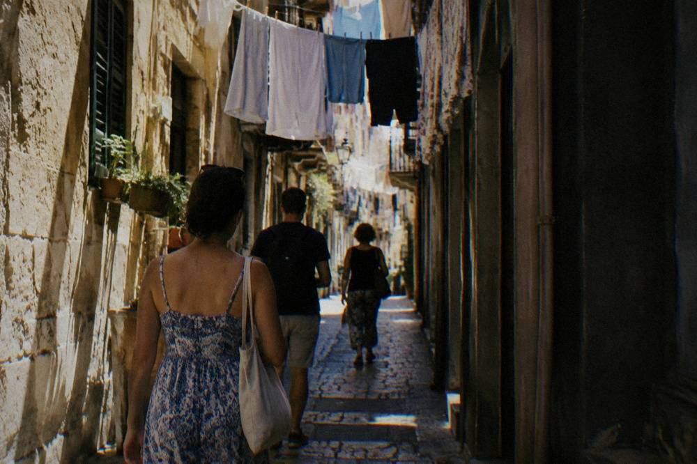 A walking tour group pauses at a baroque square in central Palermo.