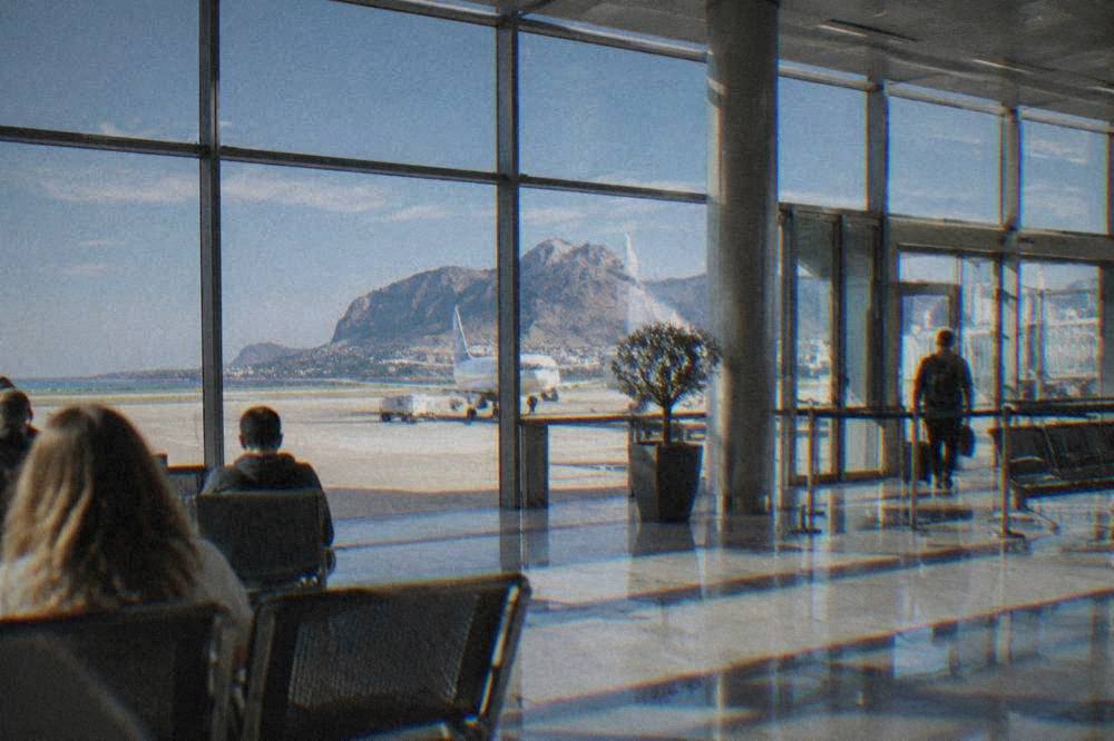 The departures hall of a small Mediterranean airport with morning light through the glass