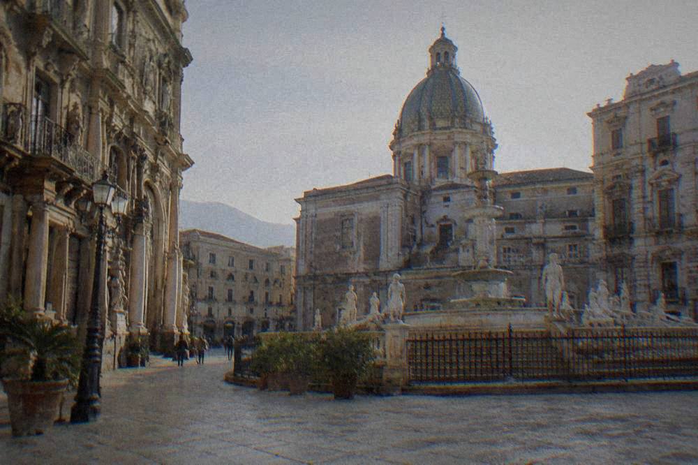 An ornate square in Palermo's old town with baroque facades under daylight