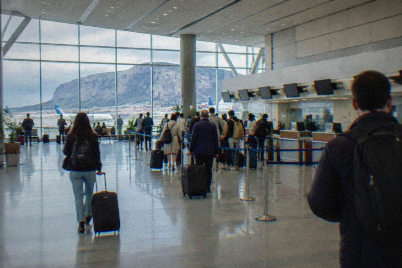 Departure hall of Palermo Falcone Borsellino airport with check-in desks and passengers with luggage