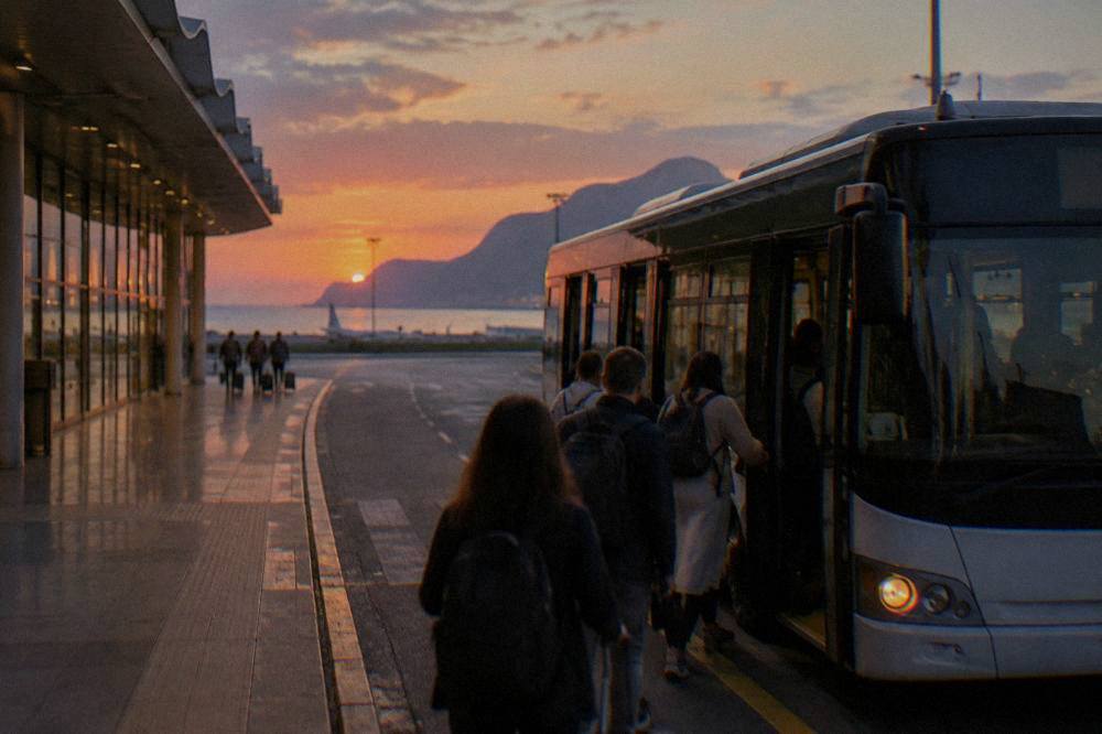 Palermo airport terminal exterior at dusk with a bus boarding passengers at the kerb