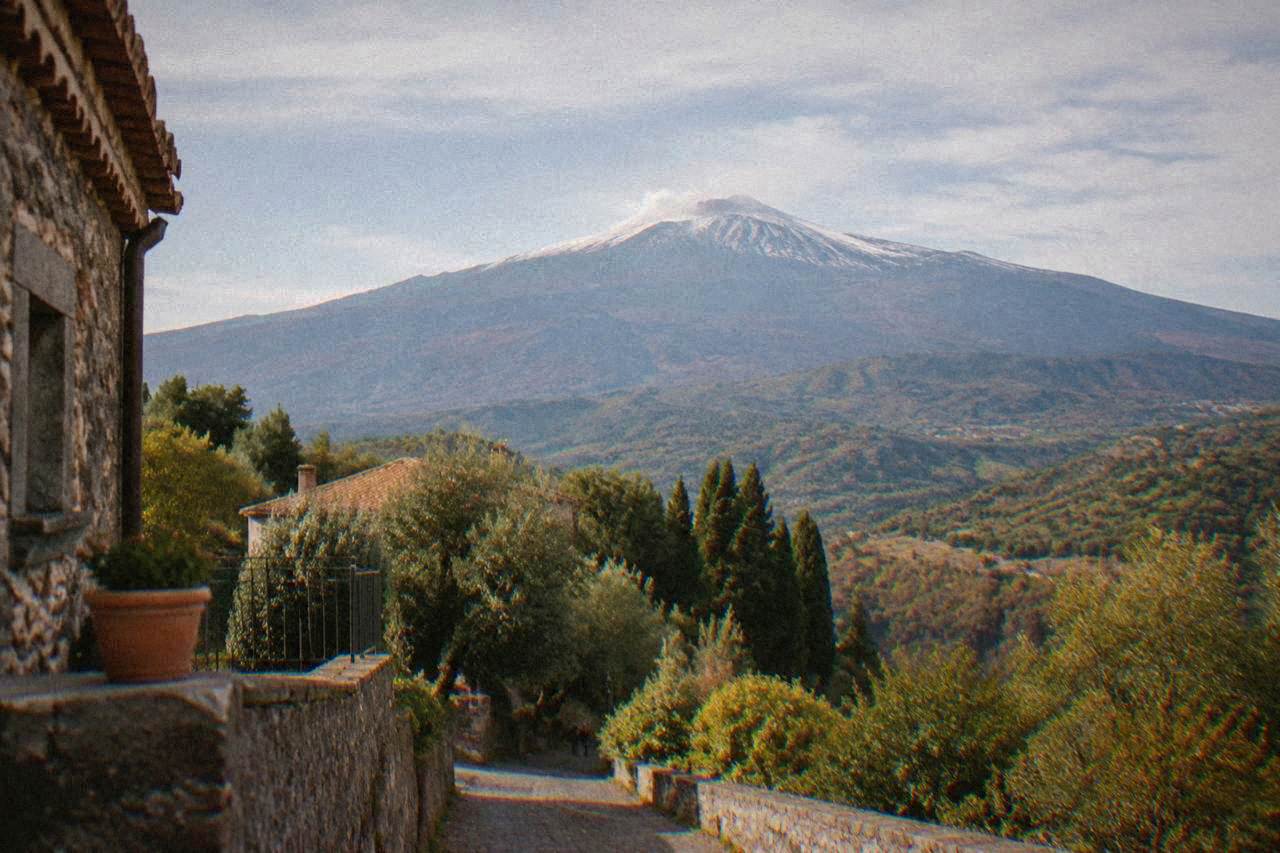 The wide cone of Mount Etna rising above wooded slopes in eastern Sicily