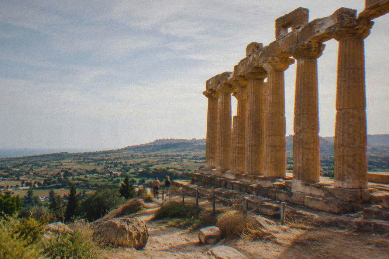 Doric temple columns standing along a ridge above farmland at the Valley of the Temples in Agrigento