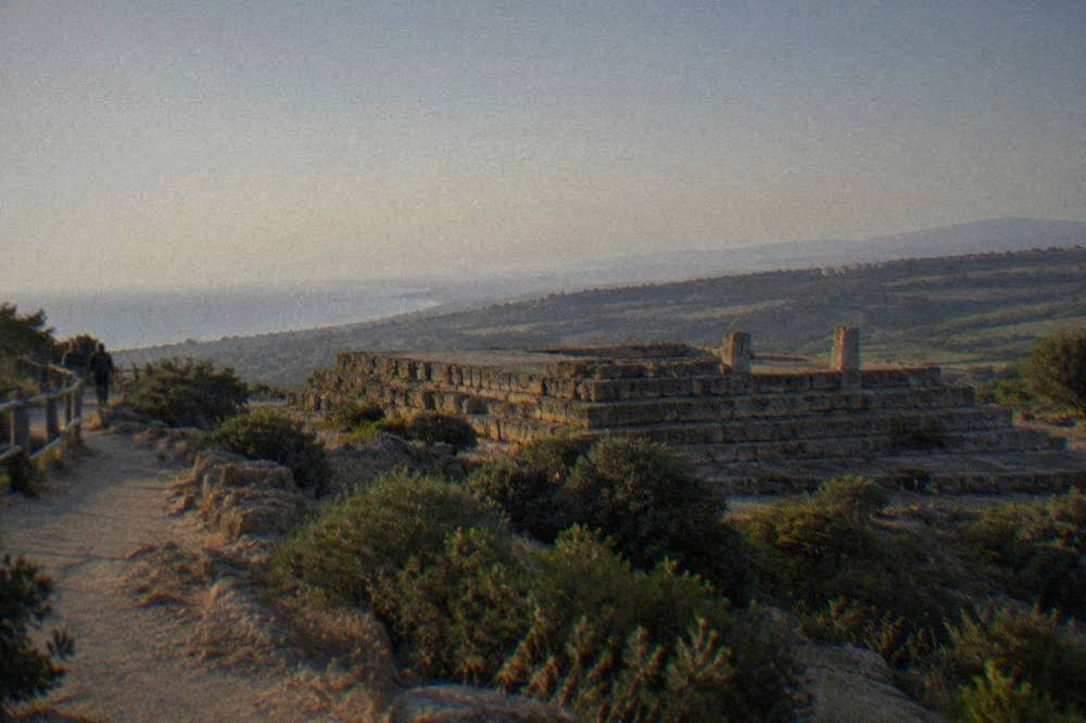A stone temple platform seen from a walking path on the ridge at Agrigento in late afternoon light