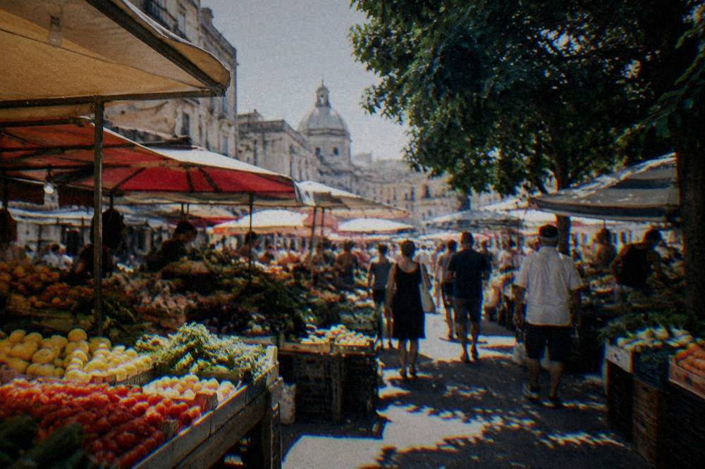 Crowded stalls of a Palermo street market with produce displays under awnings