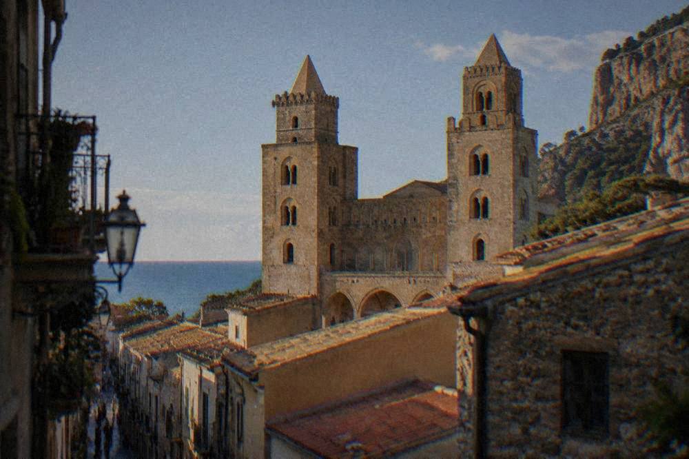 The twin-towered front of Cefalu cathedral rising above the narrow streets and rooftops of the old town