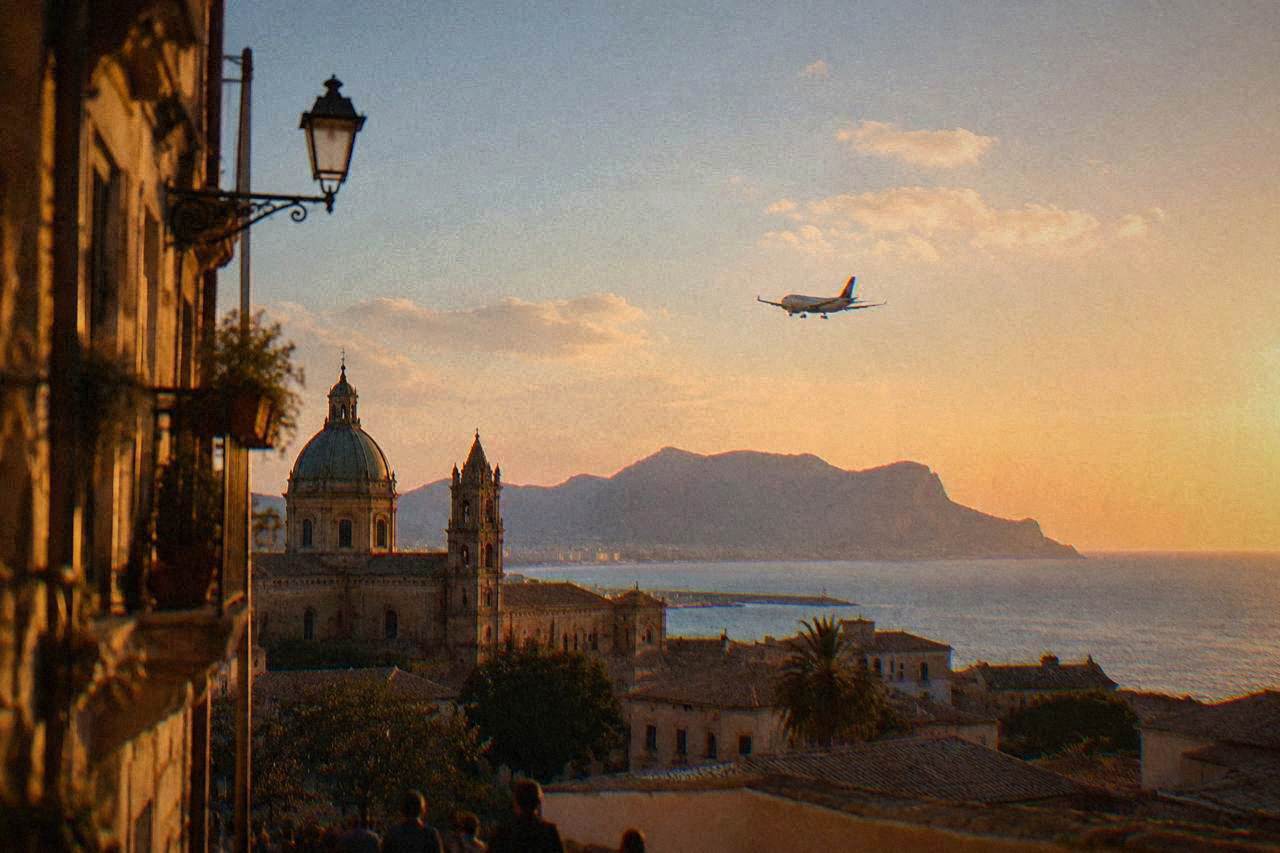 A plane on approach over the Sicilian coastline with hills and the sea in the background