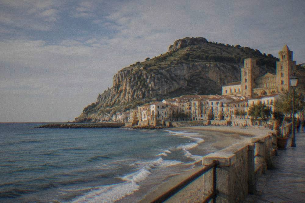 The sandy beach and rocky La Rocca headland seen from Cefalù's seafront promenade