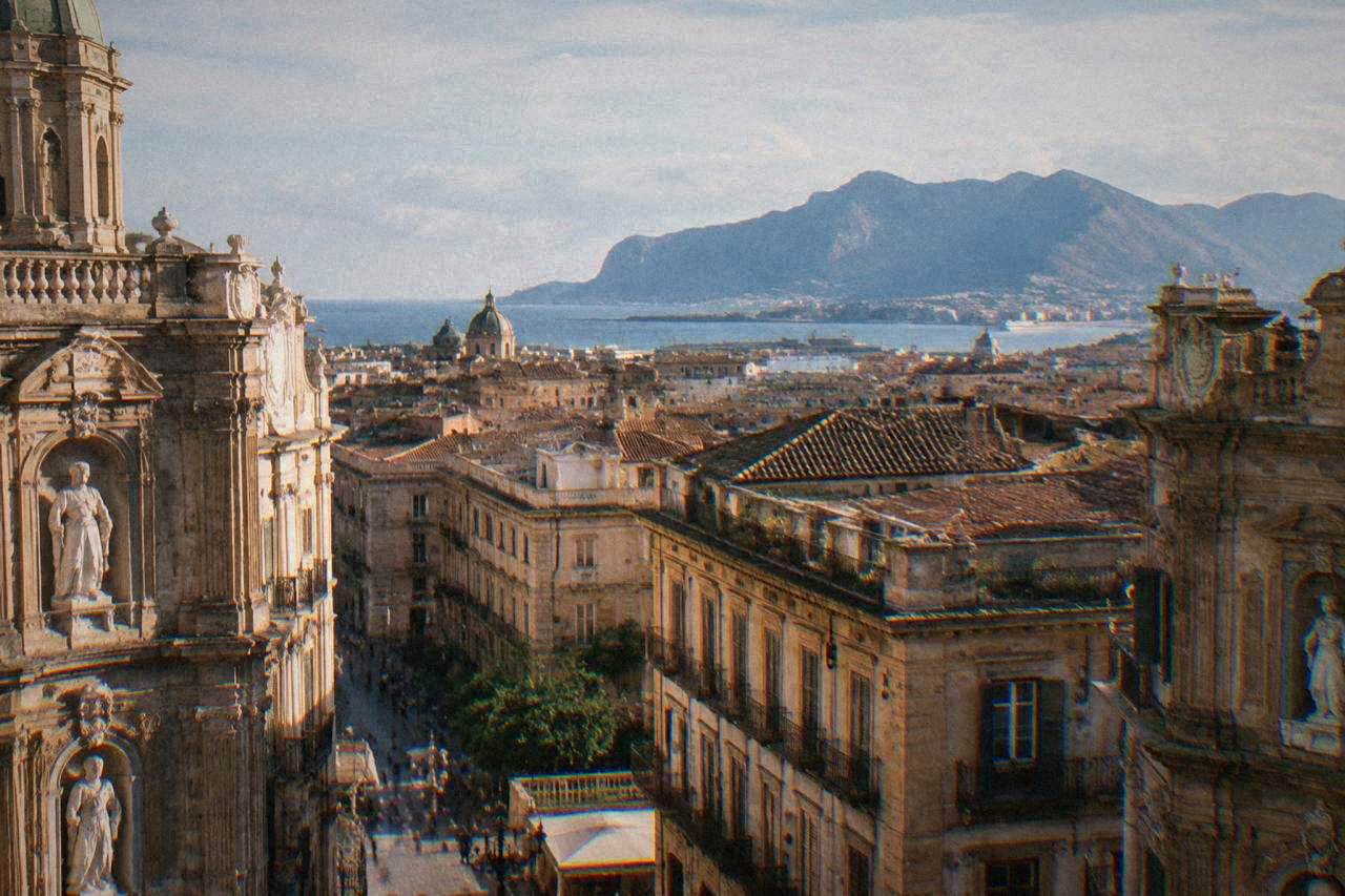 View over Palermo rooftops toward the Tyrrhenian Sea with mountains in the distance
