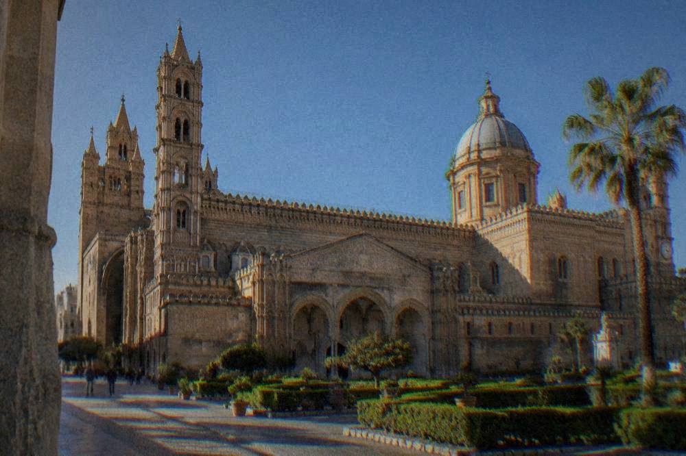 Ornate cathedral exterior with towers under a blue sky in Palermo