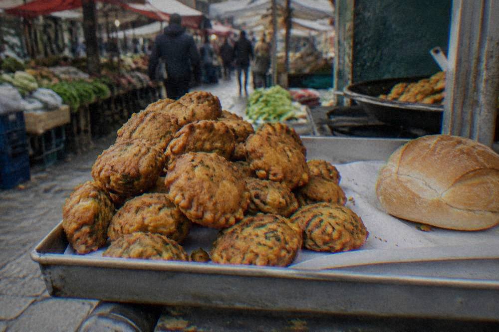 Close-up of fried chickpea fritters and a bread roll on a market food stall counter
