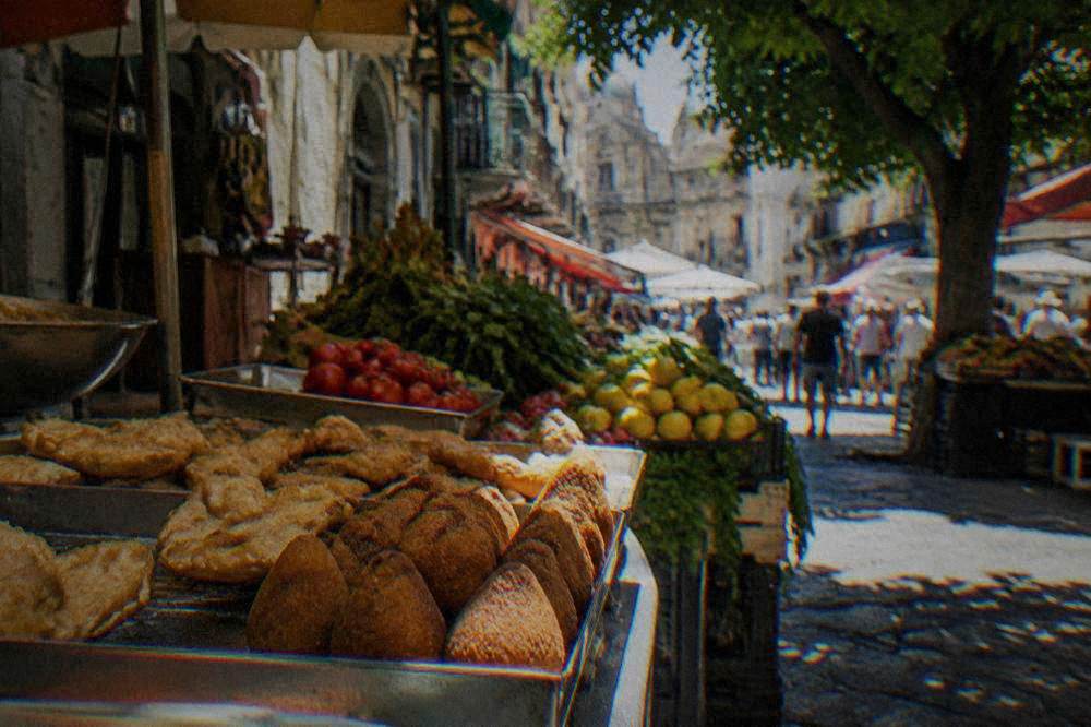 Fried street food and fresh produce on a market counter in BallarÃ²