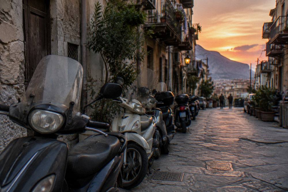 Evening light on a quiet street with parked scooters in old Palermo