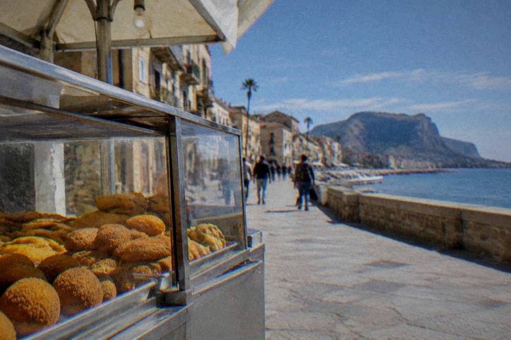 A street food stall with fried snacks displayed in a glass case