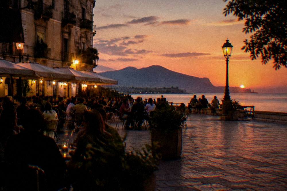 An evening square lit by bar lights with people at outdoor tables