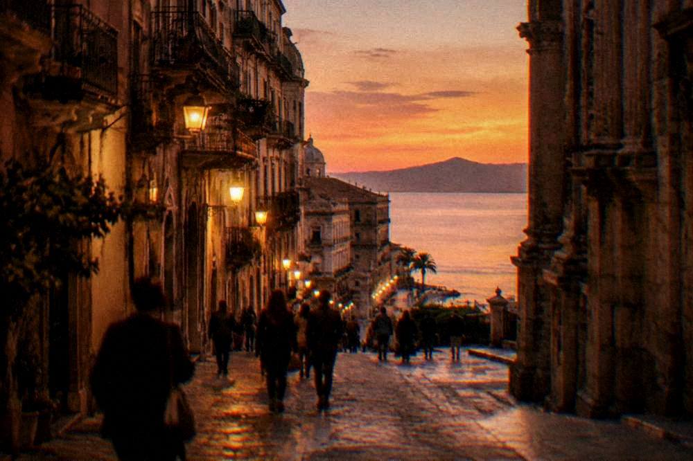 An evening street in central Palermo lit by lamps with people walking
