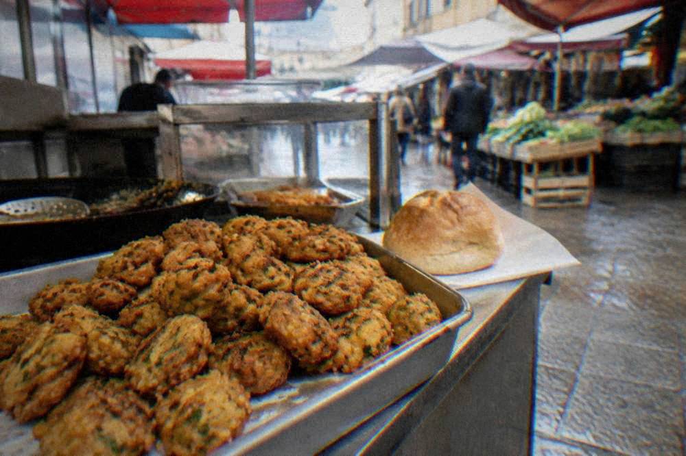 Fried chickpea fritters and a bread roll on a market counter in Palermo