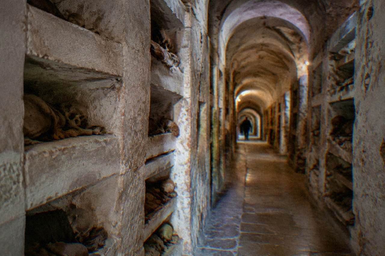 A stone corridor lined with recessed niches inside an old burial crypt