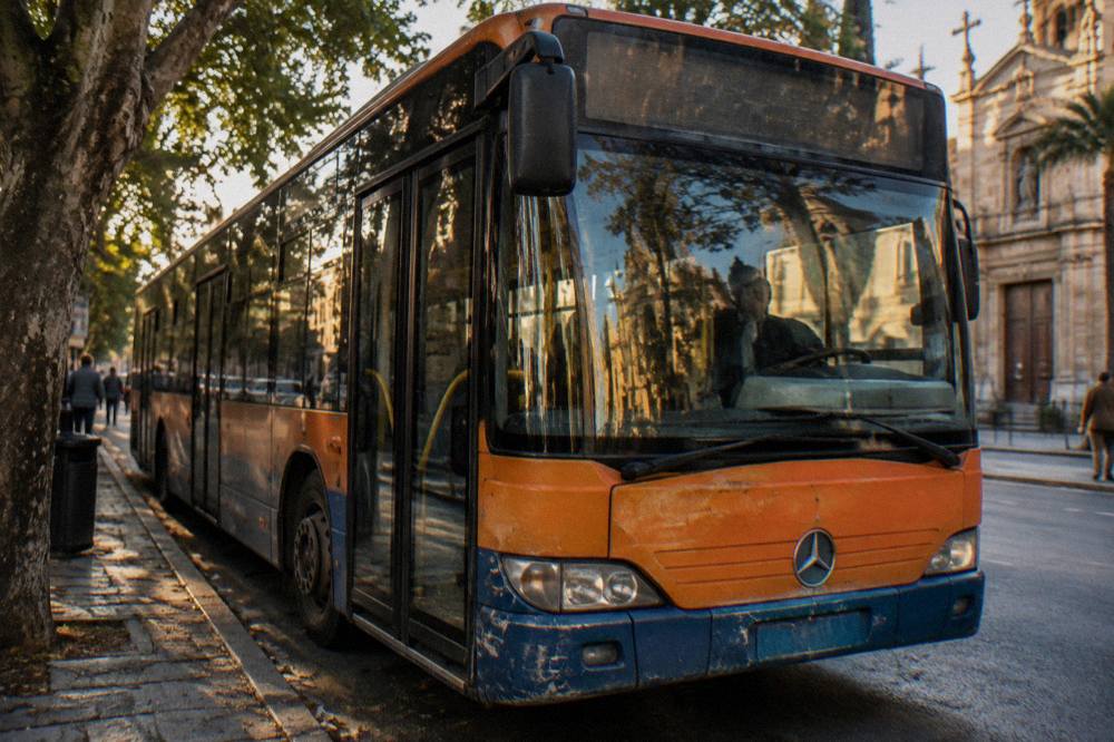 A city bus stopping on a tree-lined Palermo street near a church facade
