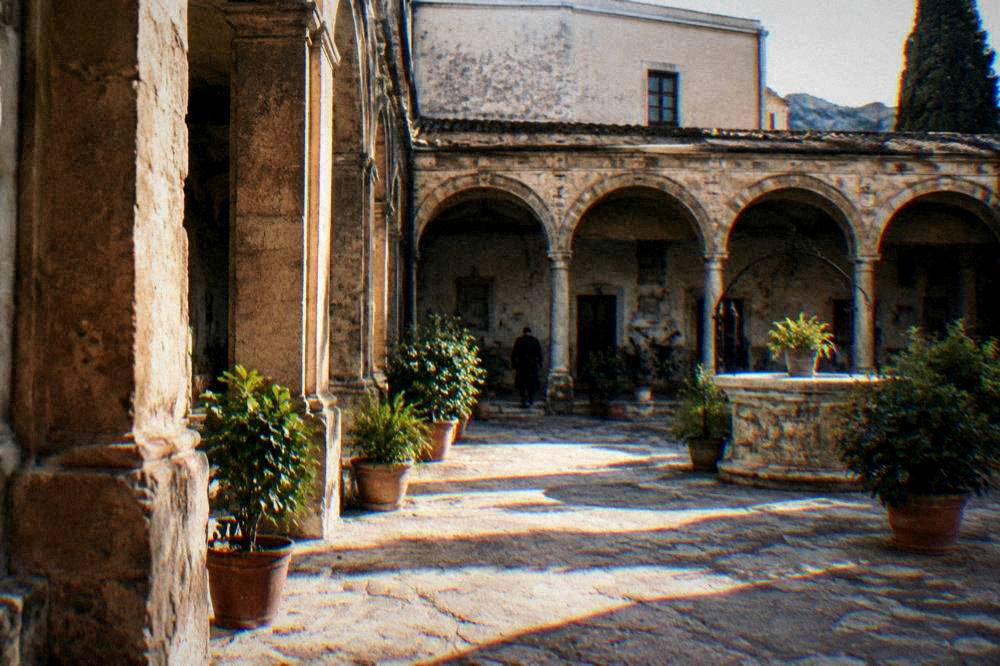 A quiet convent courtyard with stone arches and potted plants