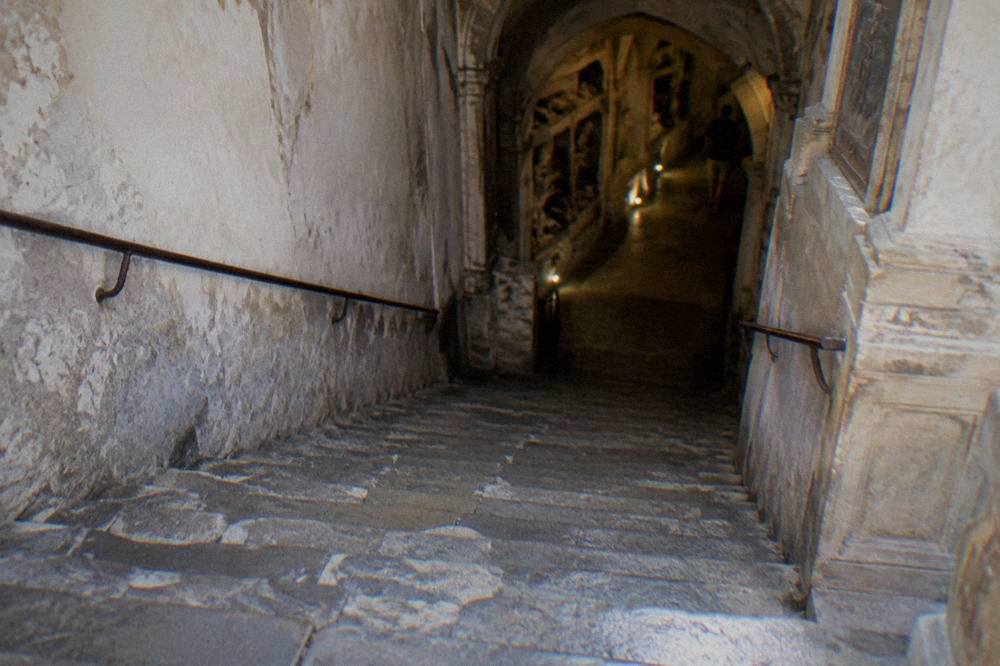 A worn stone staircase descending from a church interior toward a lower crypt level