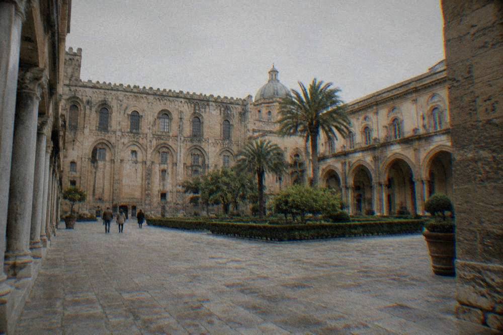 A wide stone courtyard inside the Palazzo dei Normanni complex