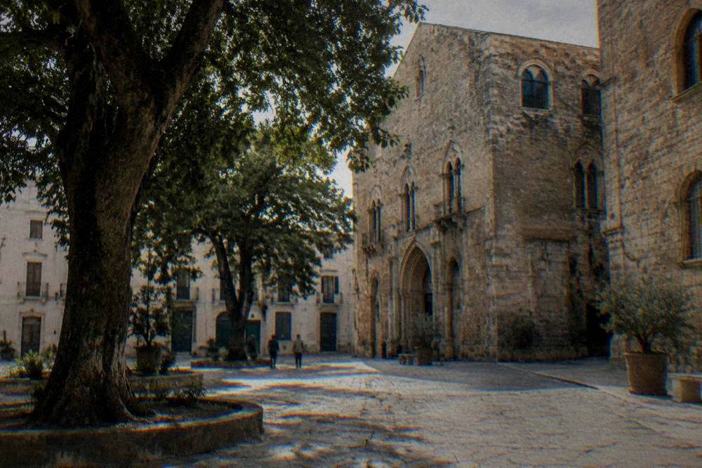 A shaded square with large trees and historic buildings in the Kalsa area of Palermo