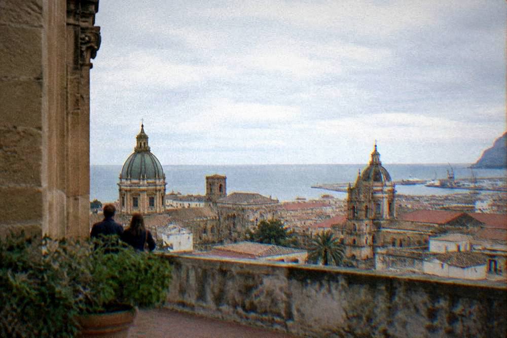 A view over rooftops and church domes toward the sea from a Palermo terrace