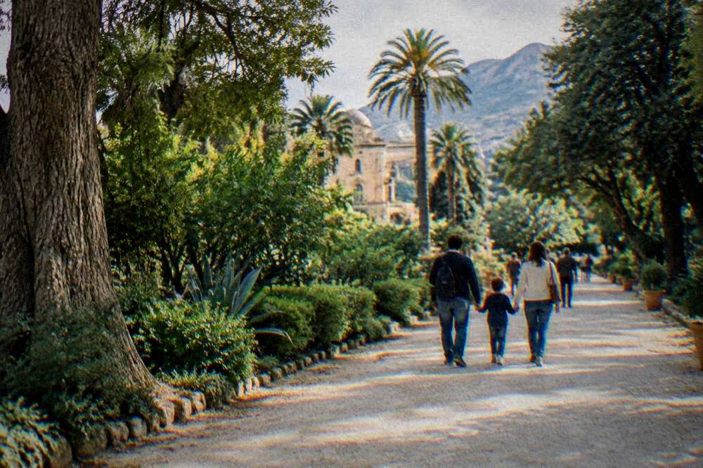 Family walking along a wide tree-lined avenue in the garden