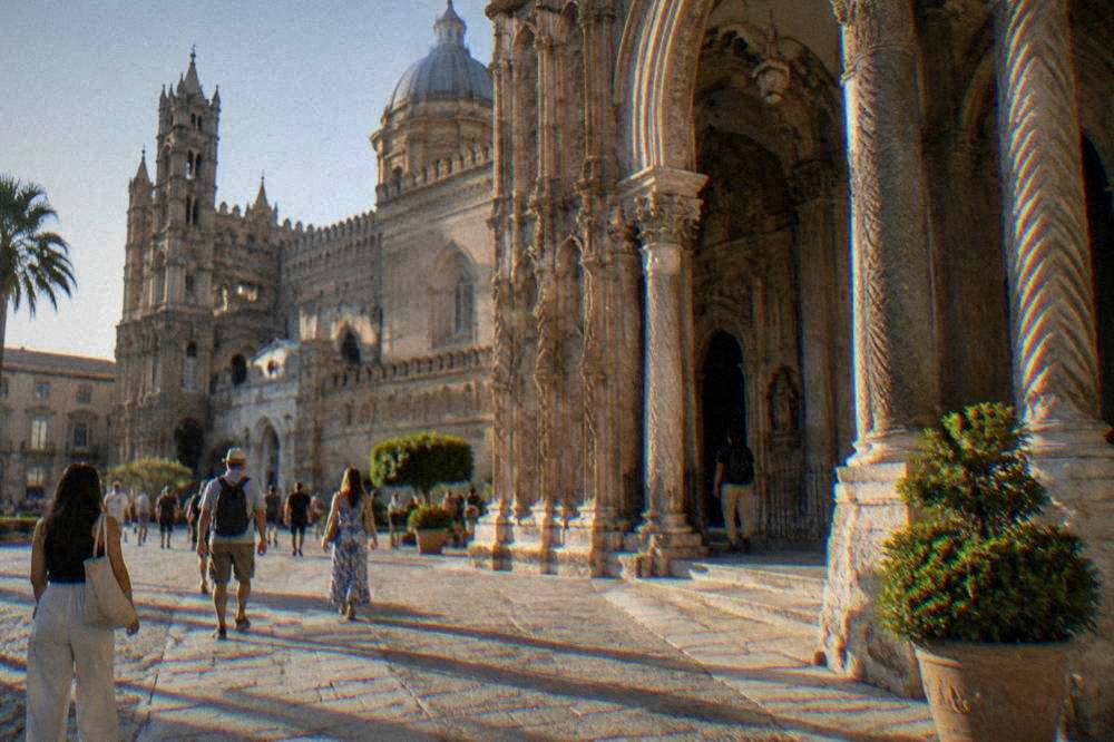 Tourists and locals passing the cathedral's southern porch with its carved columns