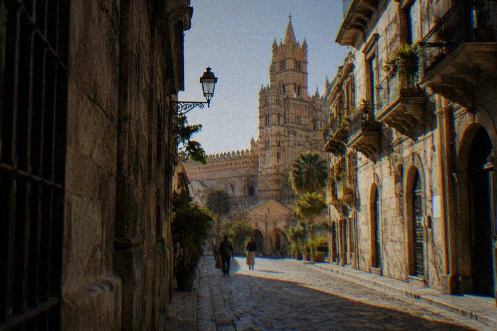 A narrow old street leading toward the cathedral tower in late afternoon