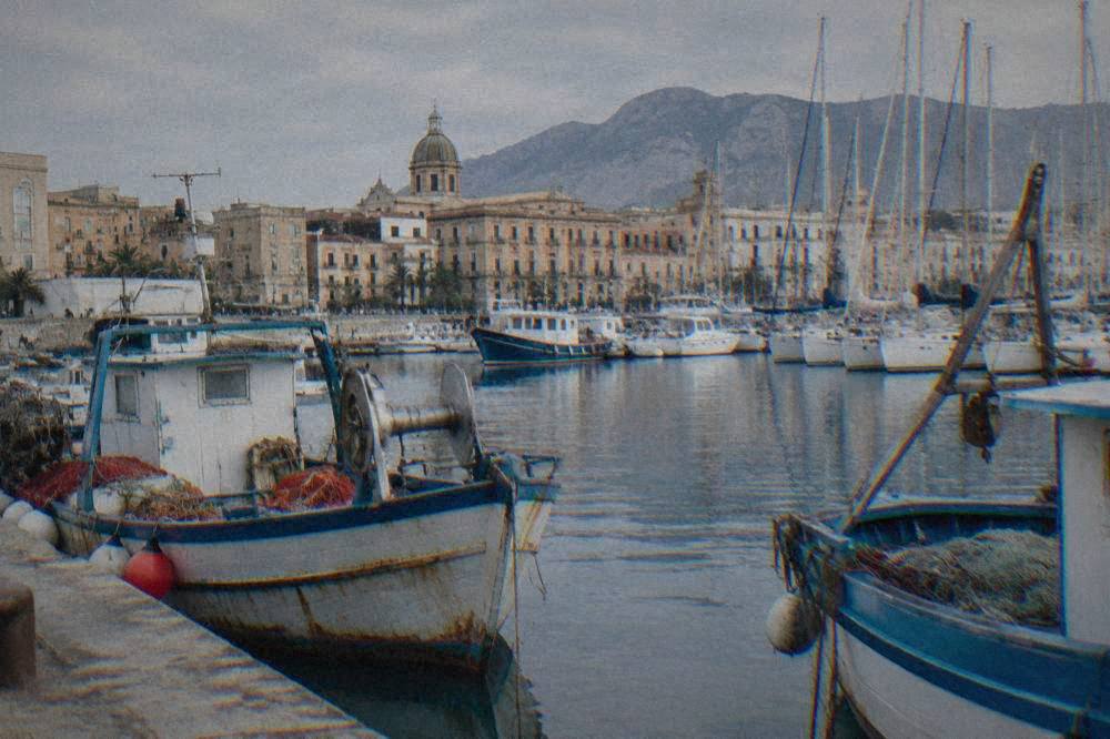 Fishing boats and masts in La Cala harbour at midday with the Palermo waterfront behind