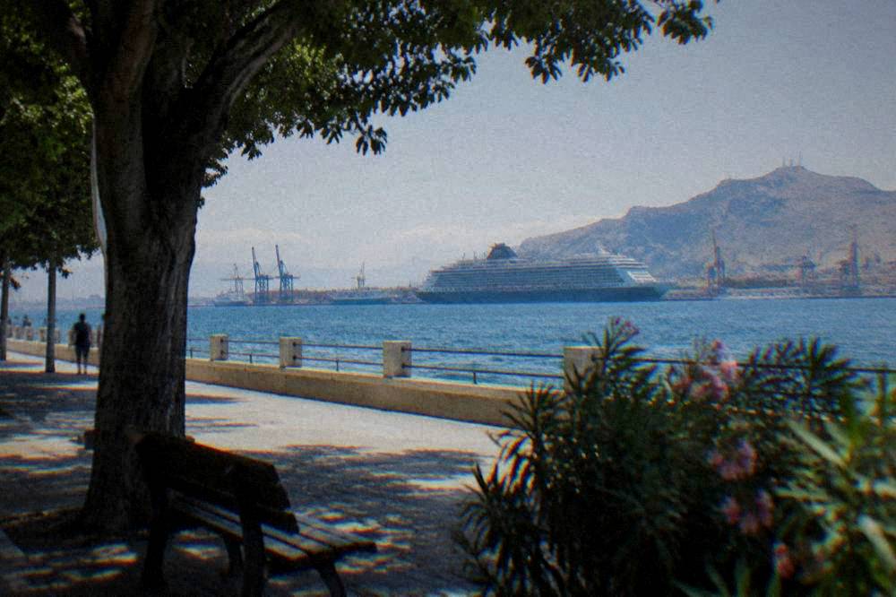 A large ferry and port cranes seen across the water from the Palermo waterfront