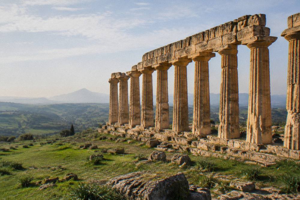 Golden ancient temple ruins standing on a ridge above open countryside in Sicily