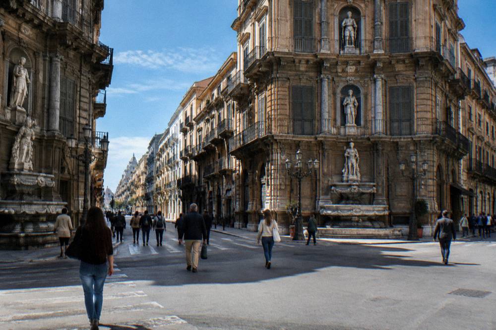 Pedestrians crossing the Quattro Canti junction with Palermo shopfronts in the background