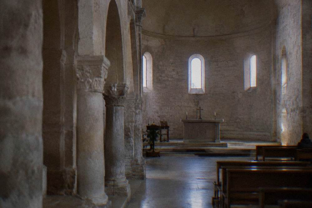 The spare stone interior of San Cataldo Church with its bare walls and simple altar