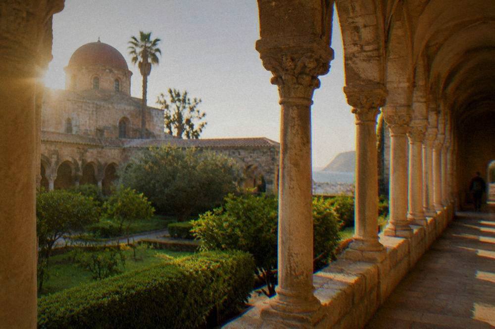 Morning light falling across the arcades of a quiet cloister garden in Palermo