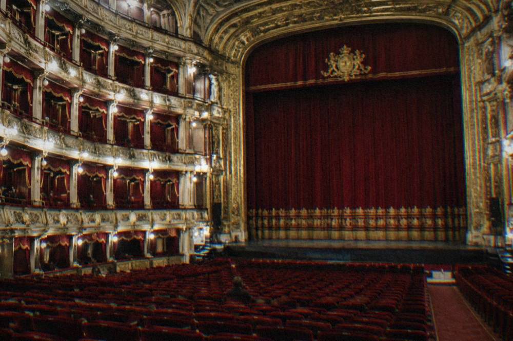The red and gold auditorium of the Teatro Massimo with rows of seats and tiered boxes
