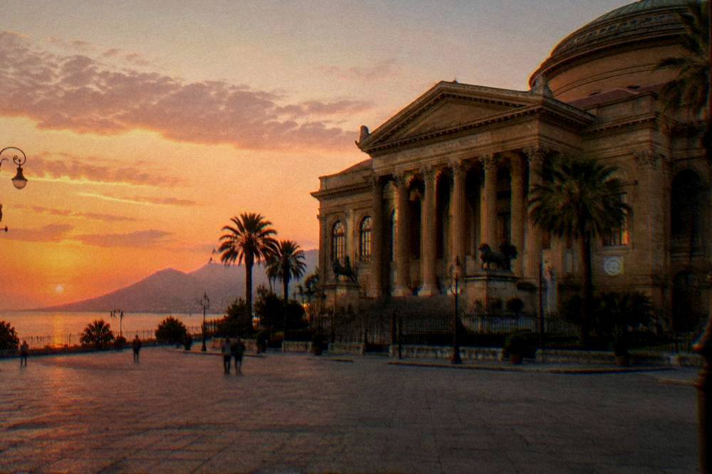 The opera house square in Palermo with the theatre facade and palm trees at dusk