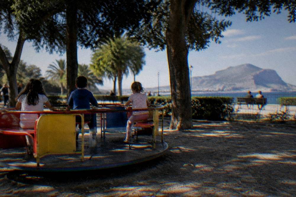 Children playing on a ride in a corner of Villa Giulia under trees