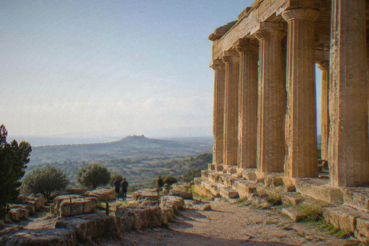 Doric temple columns on a sunny ridge overlooking open countryside
