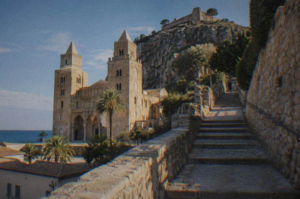 Stone steps and a walled path climbing toward the ruins on top of the La Rocca rock above Cefalu