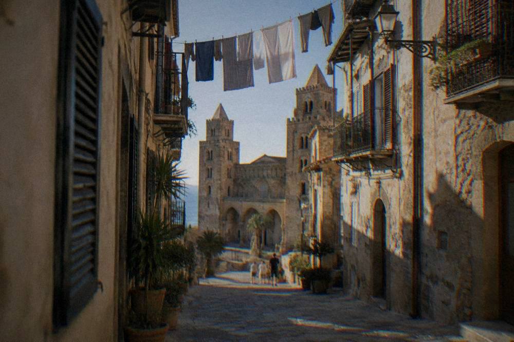 Narrow stone street in the old centre of Cefalu with shuttered houses and laundry overhead