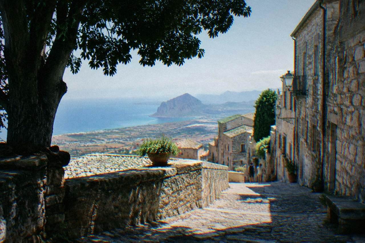 A stone hilltop town with narrow lanes sitting above coastal plains in western Sicily