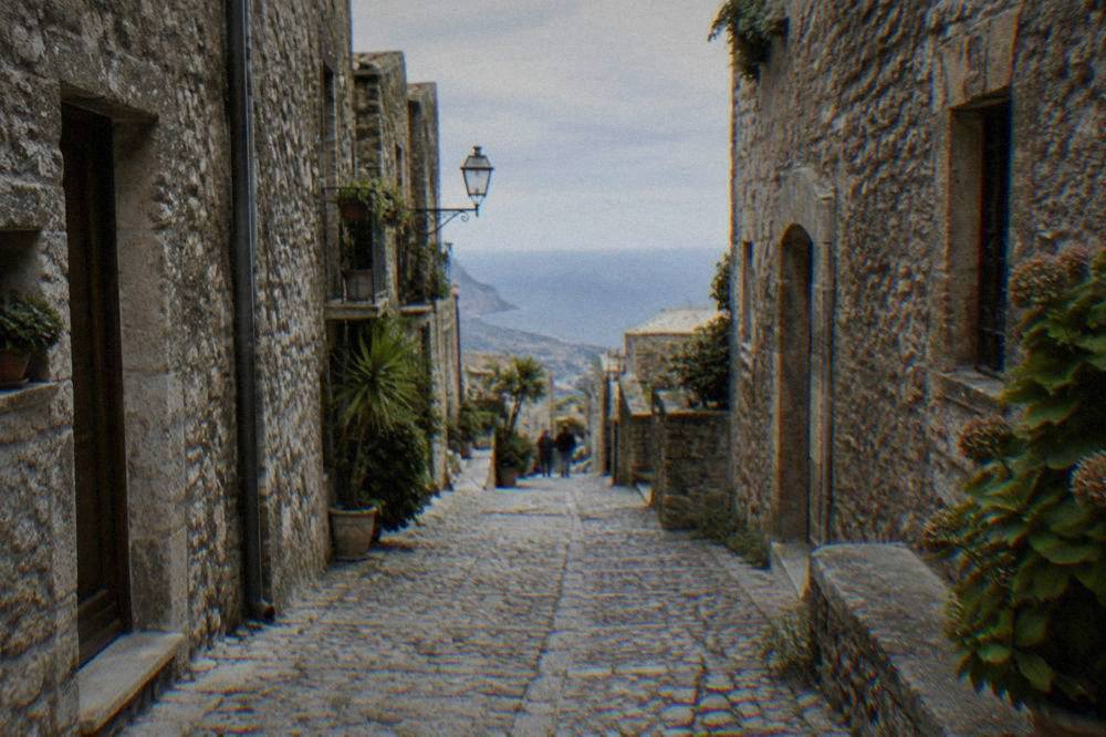 Narrow cobbled lane in a hilltop Sicilian town with stone buildings on both sides