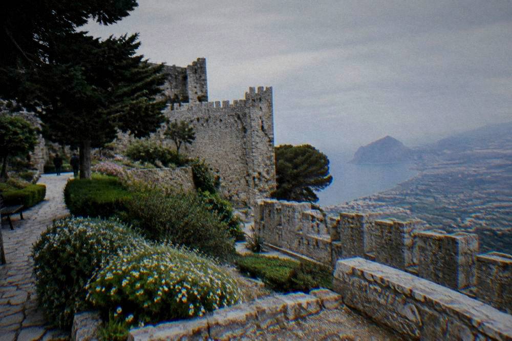 Stone castle walls and gardens at the highest point of a hilltop town