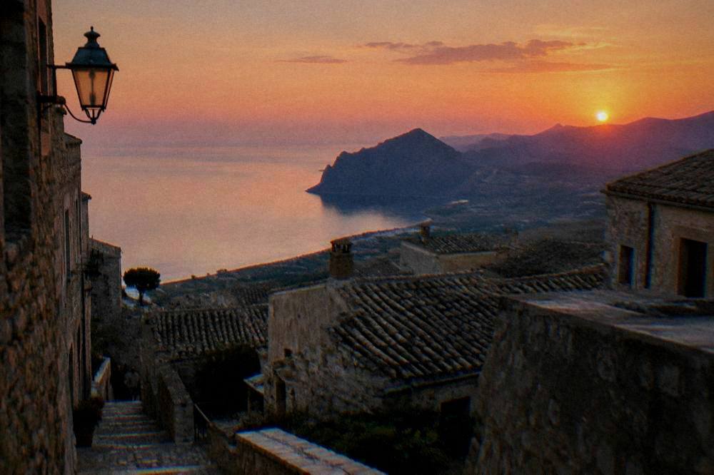 Evening light on stone rooftops of a mountain town above the sea