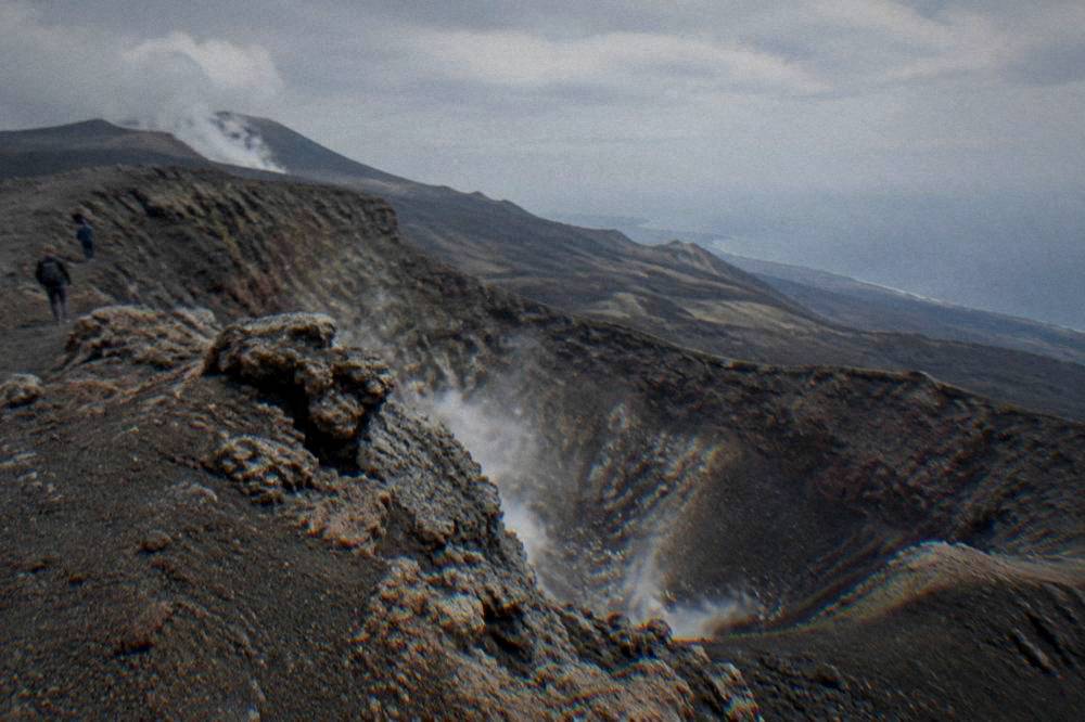 A jagged inactive crater rim on Etna with steam rising in the distance