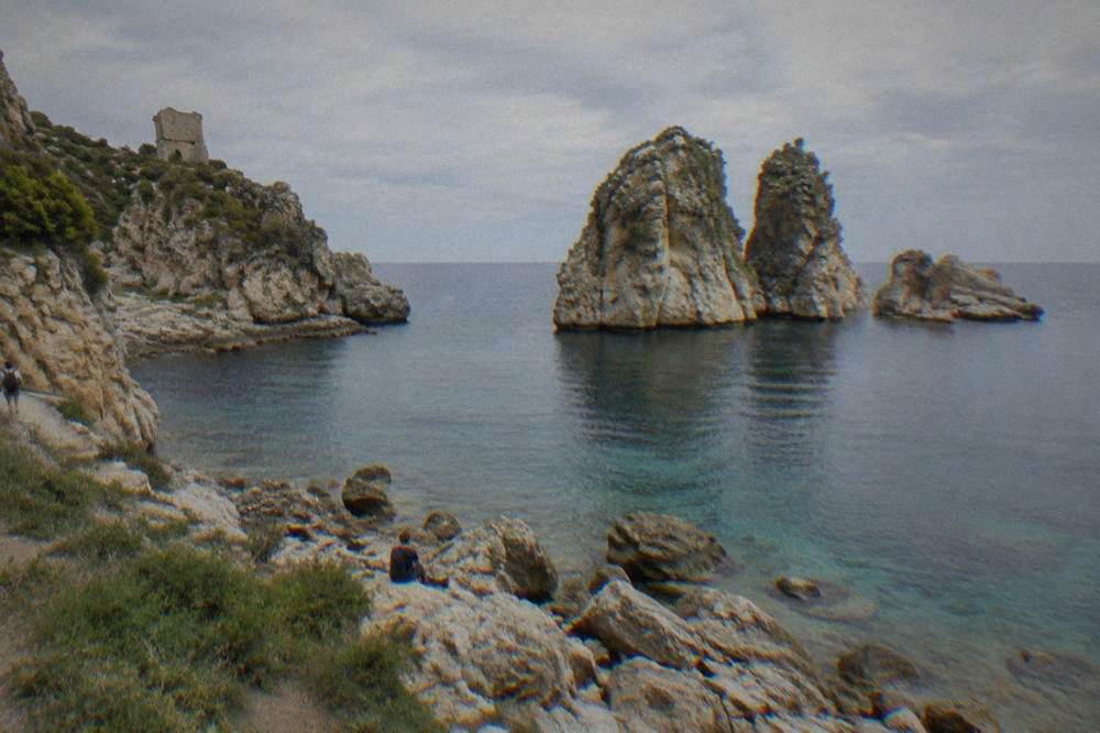 Tall rock sea stacks standing in clear water close to a rocky shore