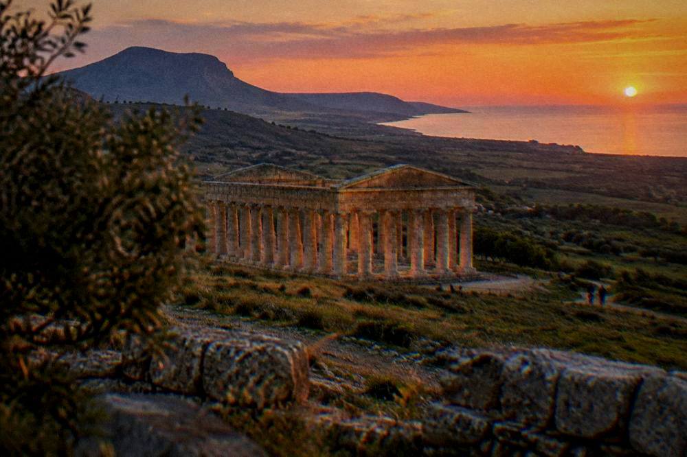 Golden evening light falling on ancient stone ruins across a wide green valley
